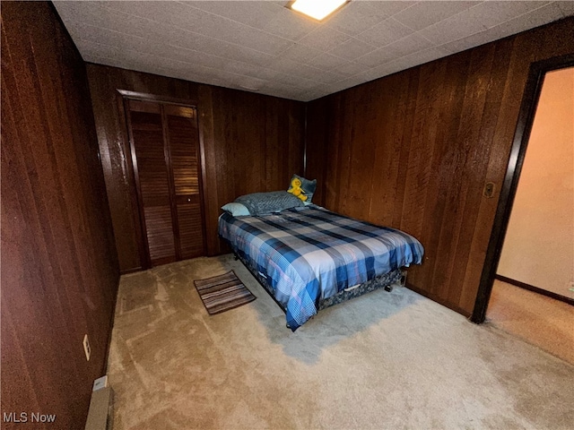 carpeted bedroom with a closet and wooden walls