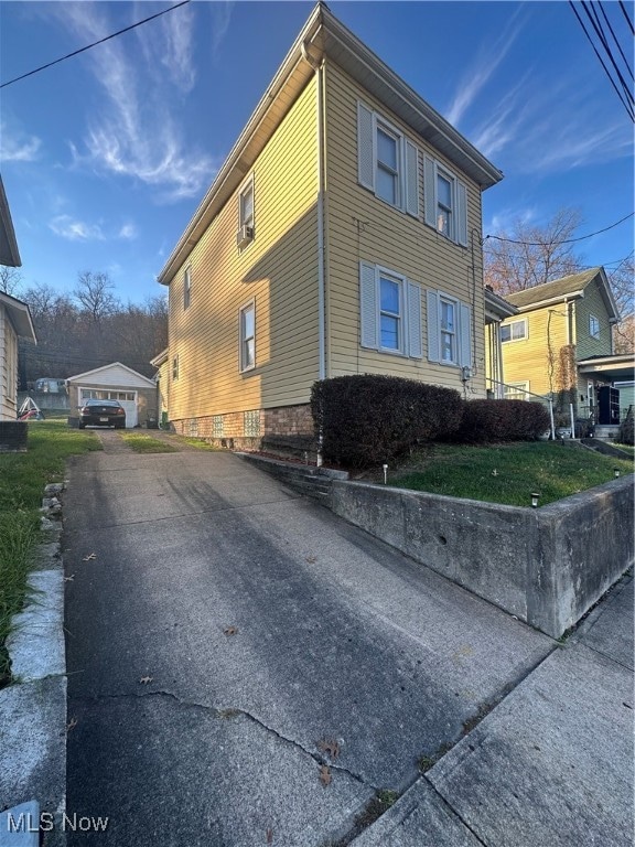 view of side of property featuring an outbuilding, a yard, and a garage