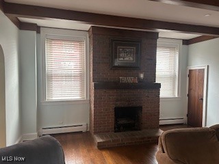 living room featuring hardwood / wood-style floors, beamed ceiling, a baseboard radiator, and a brick fireplace