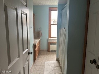 bathroom featuring a shower with shower curtain, vanity, and radiator heating unit