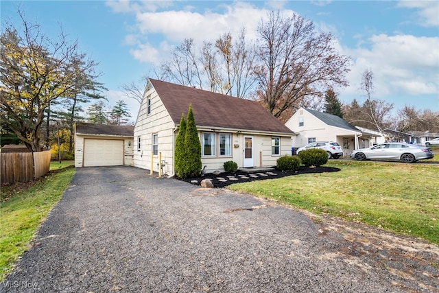 bungalow-style house with a garage, an outbuilding, and a front lawn