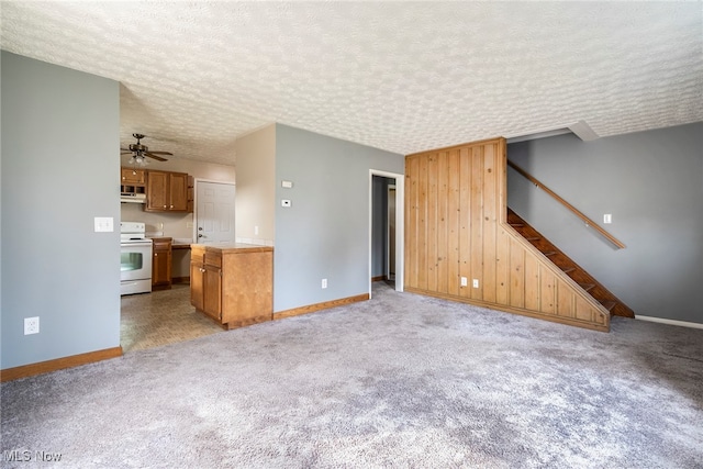 unfurnished living room featuring ceiling fan, light colored carpet, and a textured ceiling