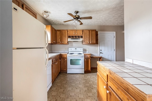 kitchen featuring a textured ceiling, white appliances, extractor fan, and tile counters