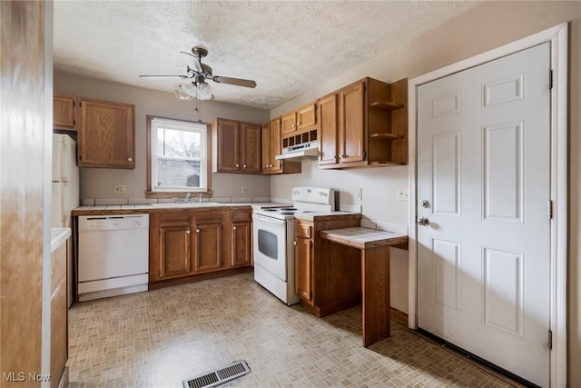 kitchen featuring tile countertops, white appliances, sink, ceiling fan, and a textured ceiling