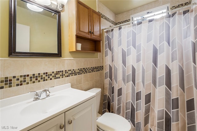 bathroom featuring vanity, curtained shower, toilet, and tile walls