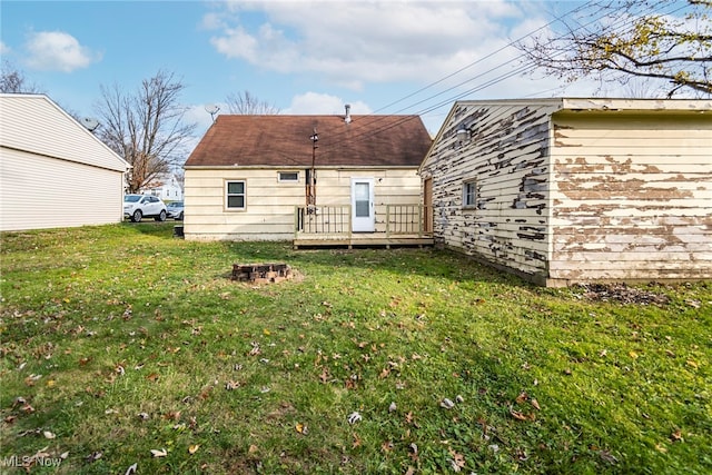 rear view of property featuring a lawn and a deck