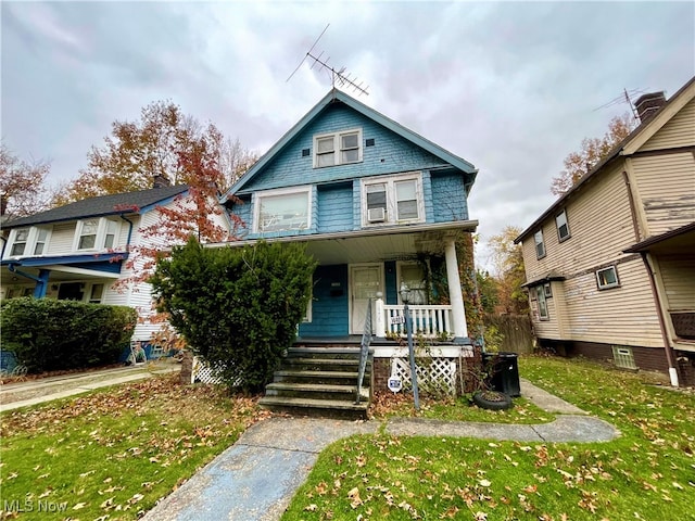 view of front of home with a porch, a front yard, and cooling unit