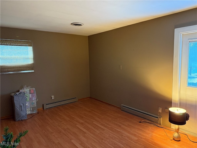 unfurnished room with wood-type flooring and a baseboard radiator