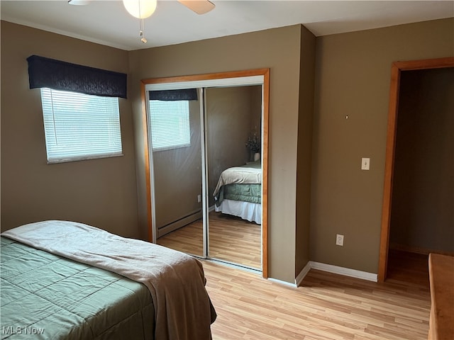 bedroom with ceiling fan, a closet, light hardwood / wood-style flooring, and a baseboard radiator