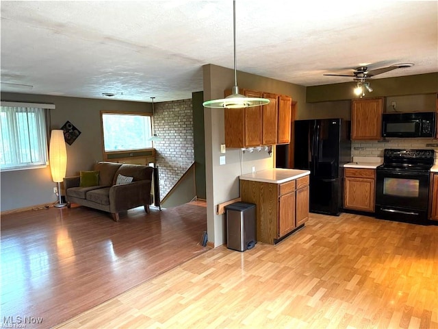 kitchen featuring pendant lighting, black appliances, a textured ceiling, and light hardwood / wood-style floors