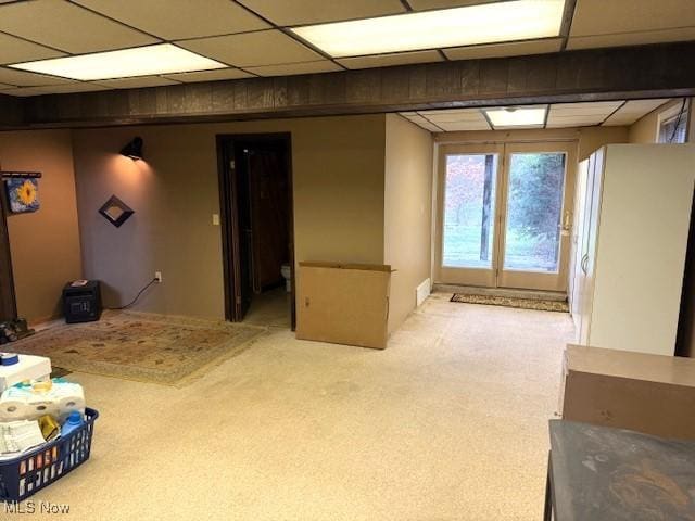 basement with a paneled ceiling and light carpet