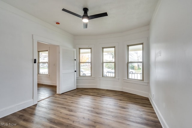 spare room featuring dark hardwood / wood-style floors, ceiling fan, and a wealth of natural light