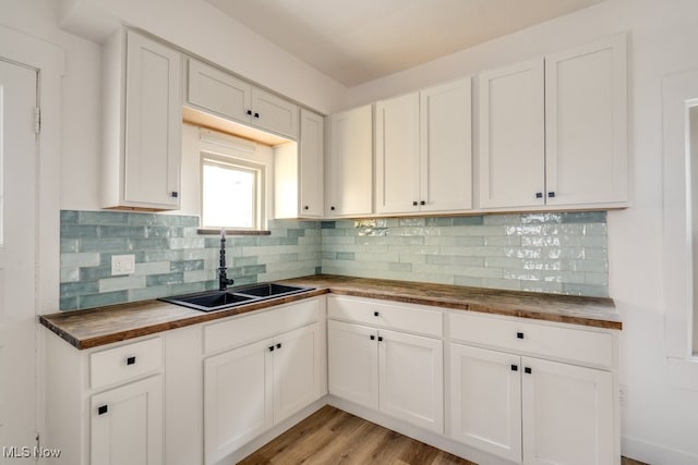 kitchen with wooden counters, light wood-type flooring, backsplash, and sink