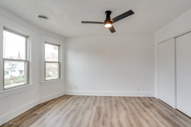 unfurnished bedroom featuring a textured ceiling, light wood-type flooring, a closet, and ceiling fan