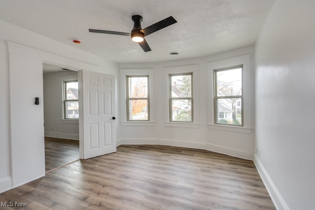 unfurnished room featuring a textured ceiling, light hardwood / wood-style floors, and ceiling fan