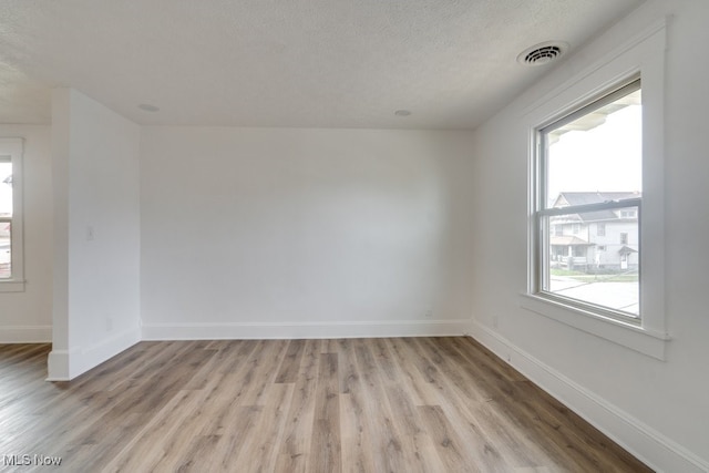 spare room with a textured ceiling and light hardwood / wood-style flooring