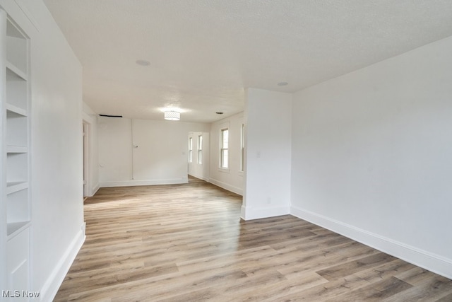 empty room with a textured ceiling and light hardwood / wood-style floors