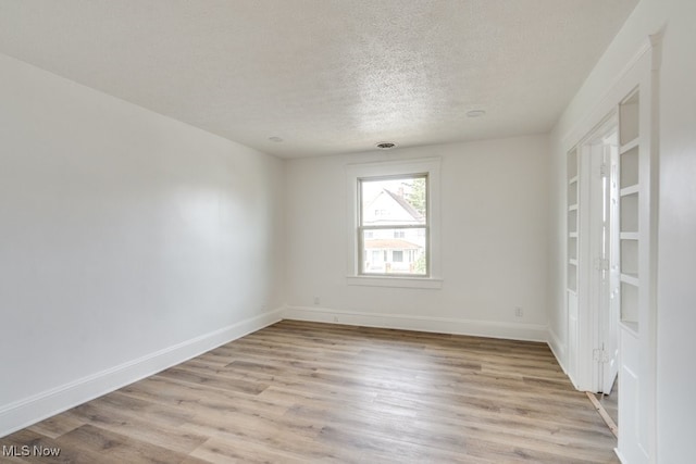 spare room featuring a textured ceiling and light wood-type flooring