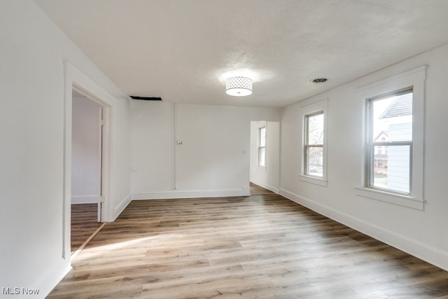 spare room featuring a textured ceiling and light hardwood / wood-style flooring