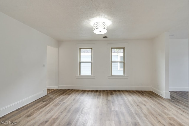 empty room featuring light wood-type flooring and a textured ceiling