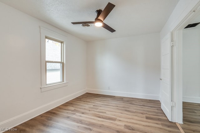 spare room featuring ceiling fan, light wood-type flooring, and a textured ceiling