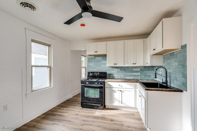 kitchen with black range oven, light hardwood / wood-style floors, white cabinetry, and sink