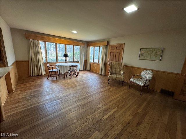 dining space featuring wood walls and dark wood-type flooring