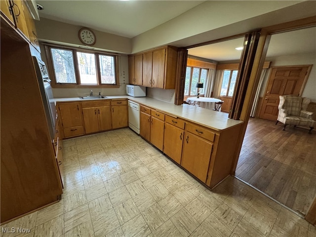 kitchen featuring sink, white appliances, kitchen peninsula, and light hardwood / wood-style flooring