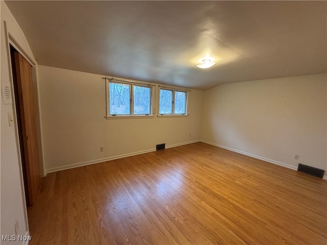 spare room featuring vaulted ceiling and light hardwood / wood-style flooring