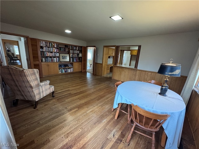 dining room featuring built in shelves, wood-type flooring, and wooden walls