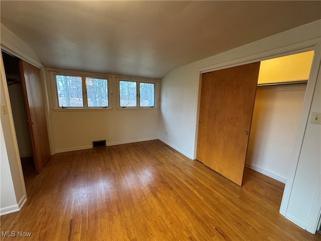 unfurnished bedroom with light hardwood / wood-style floors and lofted ceiling