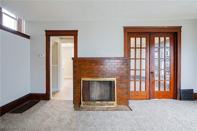 unfurnished living room with a fireplace, french doors, light colored carpet, and a textured ceiling