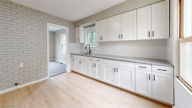 kitchen with decorative backsplash, light hardwood / wood-style flooring, white cabinetry, and sink