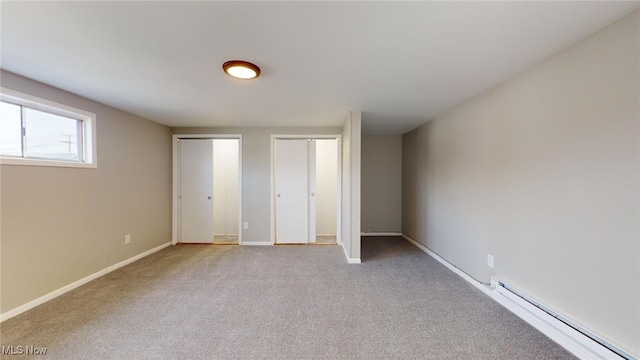 unfurnished bedroom featuring baseboard heating and light colored carpet