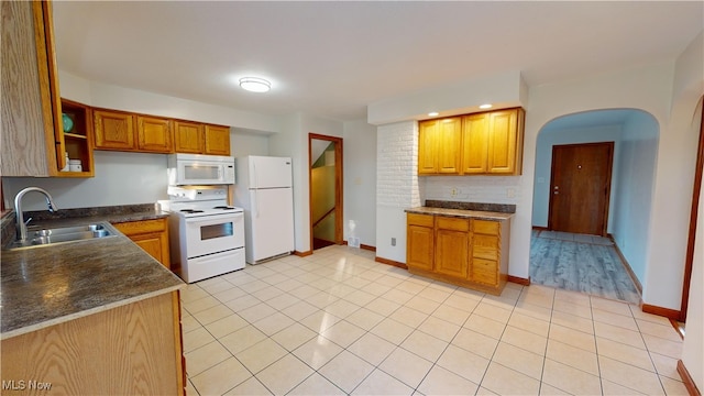 kitchen with light tile patterned floors, white appliances, and sink