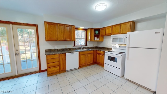 kitchen with a healthy amount of sunlight, white appliances, sink, and light tile patterned floors