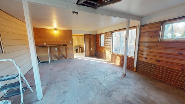 interior space featuring concrete flooring, wooden walls, and brick wall