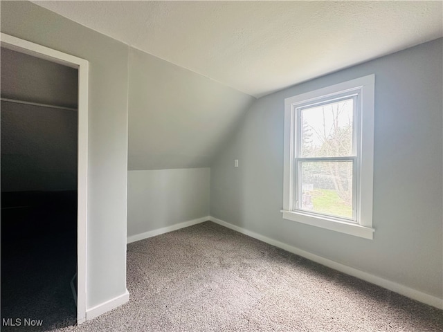 bonus room with carpet flooring, lofted ceiling, and a textured ceiling