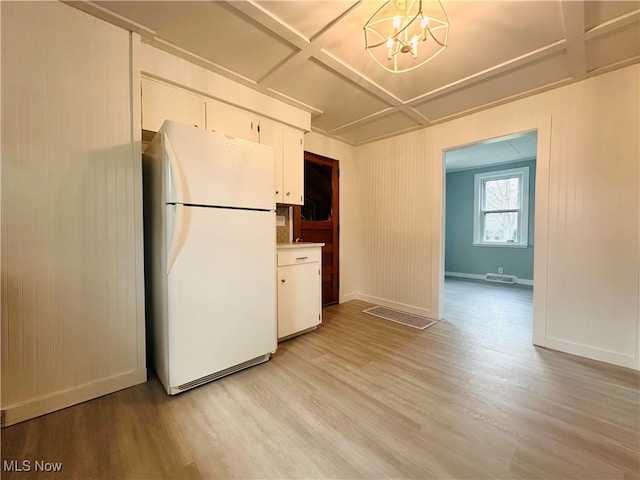 kitchen with white cabinets, white fridge, and light hardwood / wood-style floors