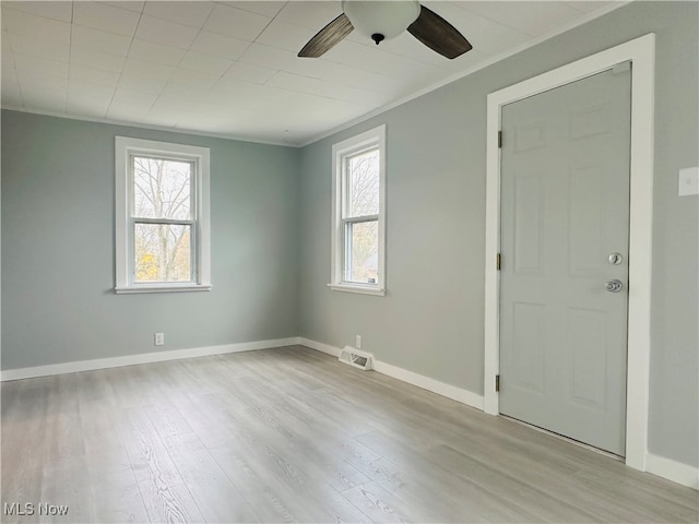 spare room with a wealth of natural light, crown molding, ceiling fan, and light wood-type flooring