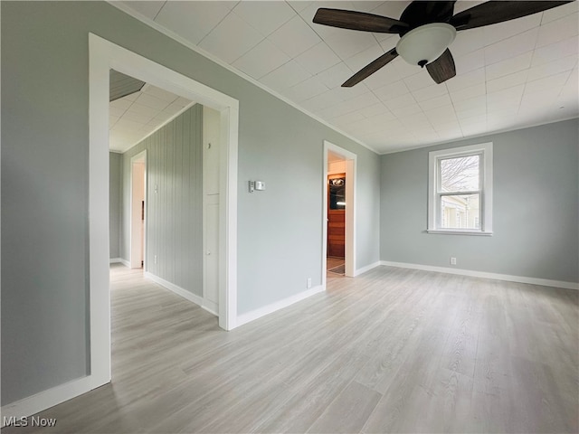 unfurnished room with ceiling fan, wooden walls, ornamental molding, and light wood-type flooring