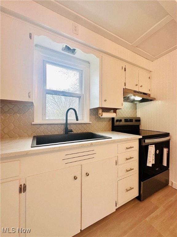 kitchen featuring black range with electric stovetop, white cabinetry, sink, and light hardwood / wood-style flooring