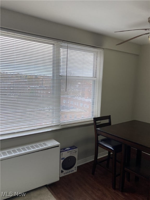 dining space with ceiling fan, radiator heating unit, and dark wood-type flooring