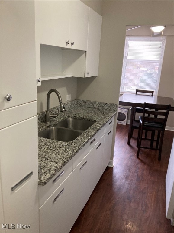 kitchen featuring dark hardwood / wood-style flooring, white cabinetry, sink, and light stone countertops