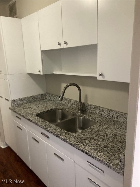 kitchen featuring white cabinetry, sink, dark stone counters, and dark hardwood / wood-style floors