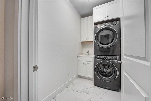 clothes washing area featuring stacked washer / dryer, sink, and cabinets