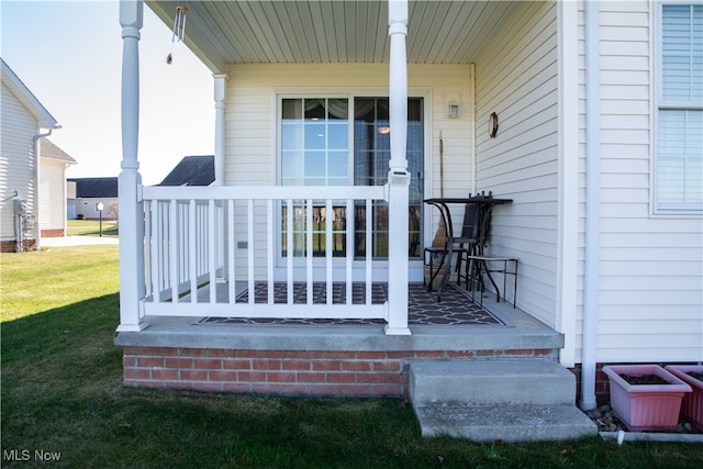 view of exterior entry with covered porch and a yard