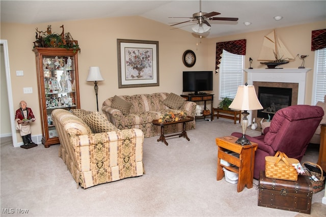 carpeted living area featuring vaulted ceiling, a glass covered fireplace, a ceiling fan, and baseboards