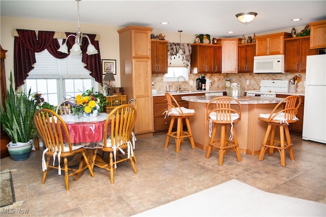 kitchen with a wealth of natural light, a kitchen island, pendant lighting, and white appliances