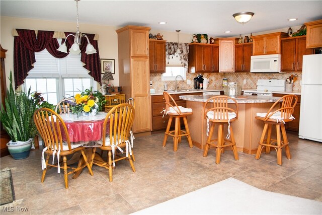 kitchen with a wealth of natural light, light countertops, a kitchen island, a sink, and white appliances